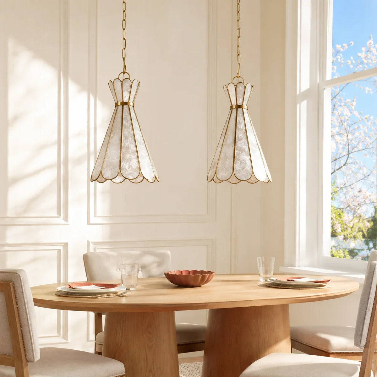 Two centered Mira Capiz shell pendant lights over a sunlit round dining table