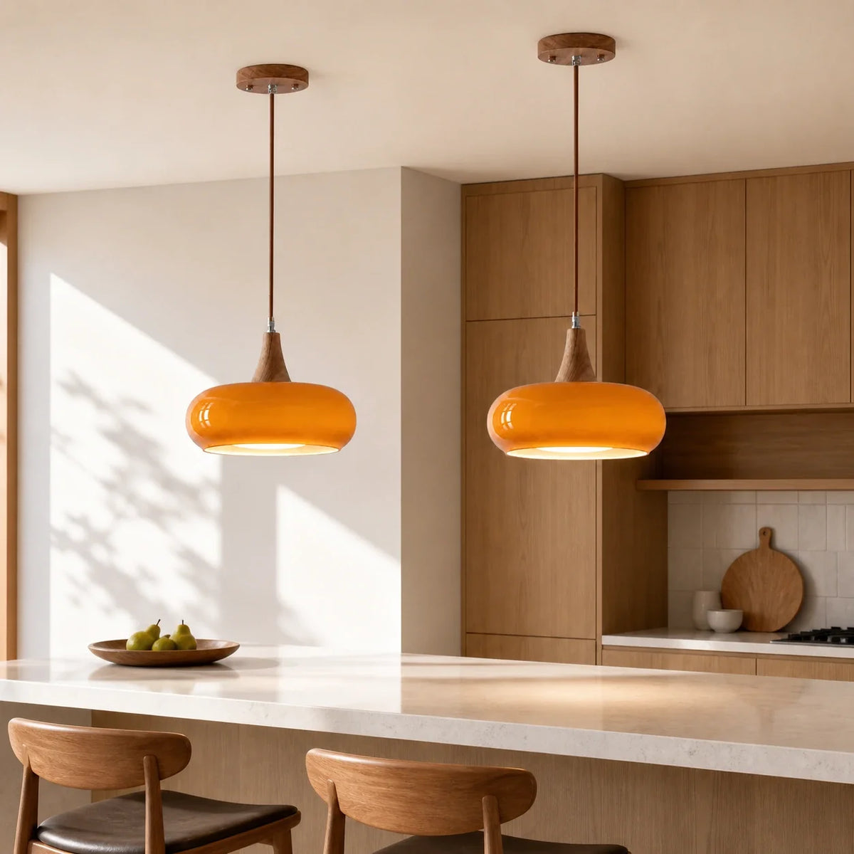 Pair of orange Marie dome glass pendants over a kitchen island