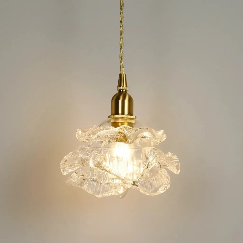 Decorative pendant light with floral glass shade and brass fitting on a neutral background